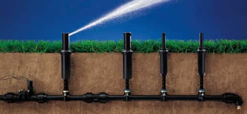 Immagine di un impianto di irrigazione, con tubi, valvole e una pompa che fornisce acqua a un campo coltivato